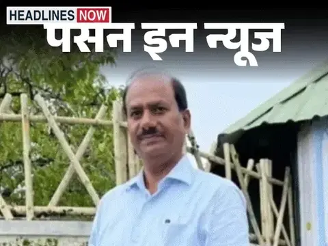 नीली शर्ट पहने एक व्यक्ति आउटडोर में खड़े हुए दिखाई दे रहे हैं