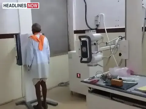 एक अस्पताल के कमरे में एक्स-रे मशीन के सामने खड़ा व्यक्ति